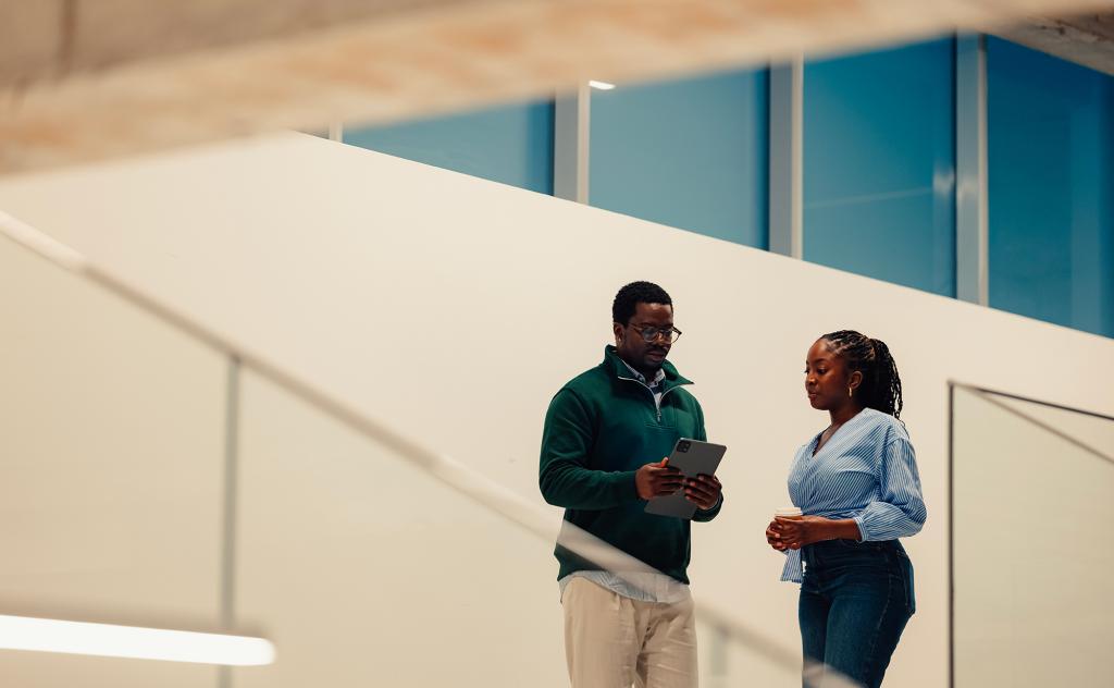 Two colleagues collaborating, standing in hallway